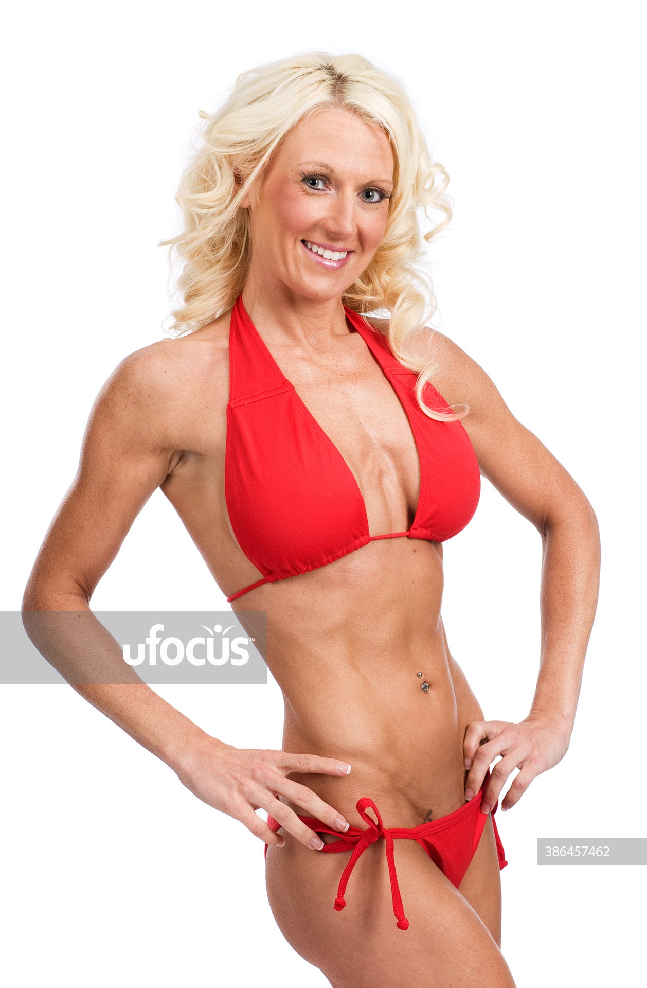 Beautiful female fitness model showing muscular abs in red bikini stock photo